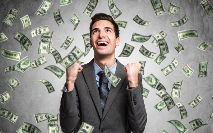 Persona joven celebrando el éxito financiero con billetes y gráficos de crecimiento, simbolizando cómo ser millonario en Perú.